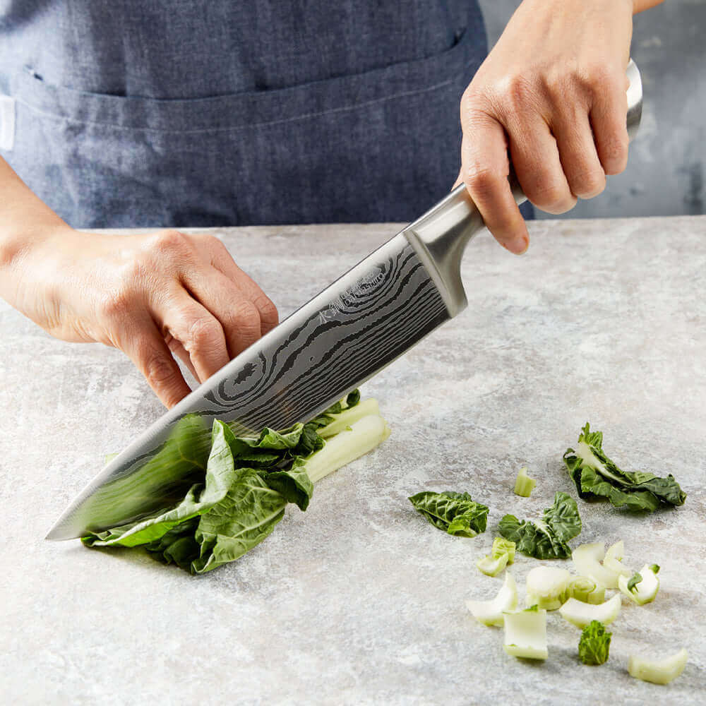 Chef using Cuisine::pro® Damashiro® 20cm/8" Chefs Knife to chop leafy greens on a cutting board.