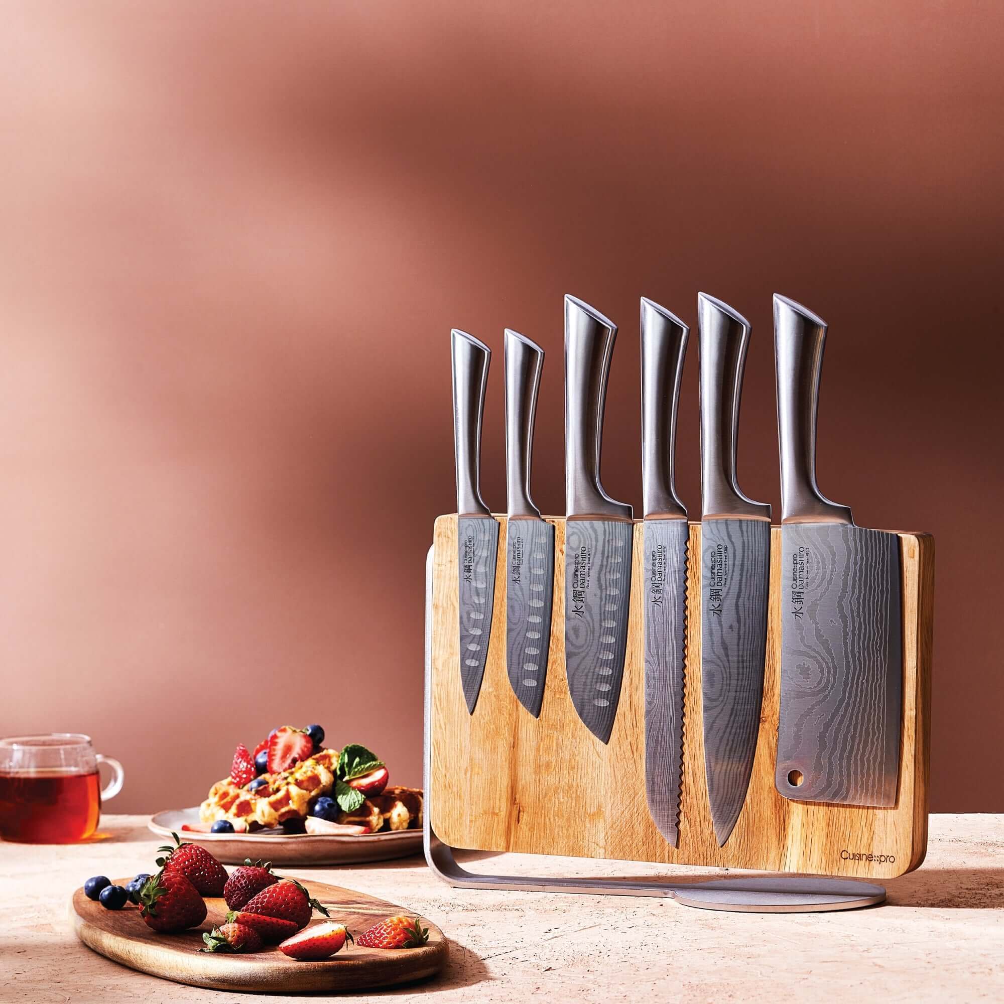 Cuisine::pro® Damashiro® Meiyo 7 piece knife block with 6 Japanese steel knives displayed on a wooden counter with fruit and waffles.